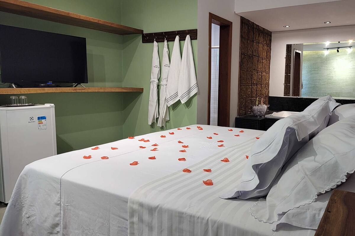 A hotel room with a bed, a television, a minibar, and a bathroom visible through an open door.