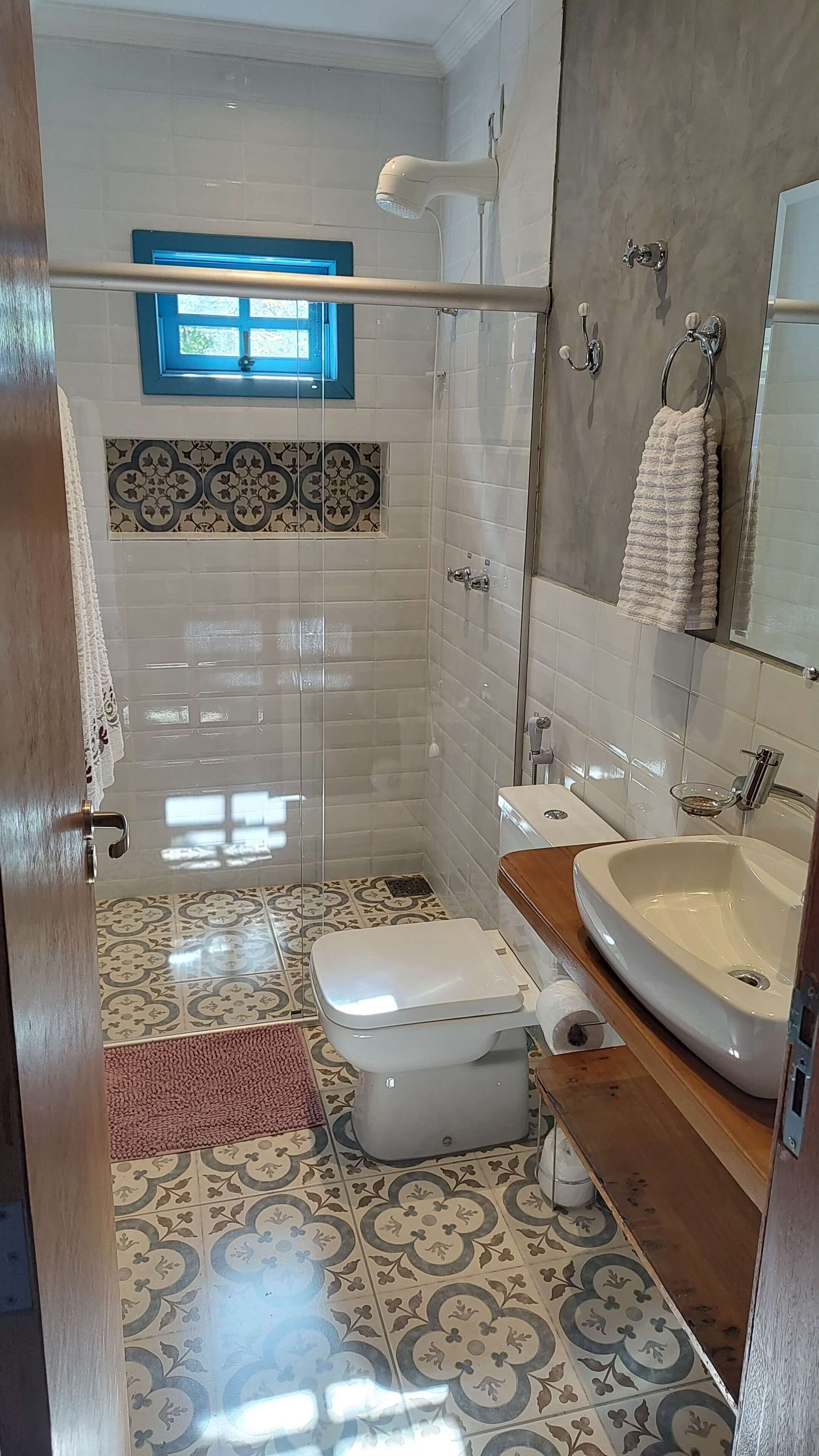 Baño con ducha, inodoro, lavamanos y ventana.