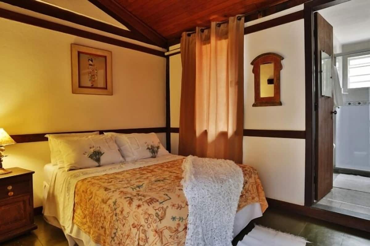 A bedroom with a bed, a nightstand, a mirror, and a door leading to a balcony.