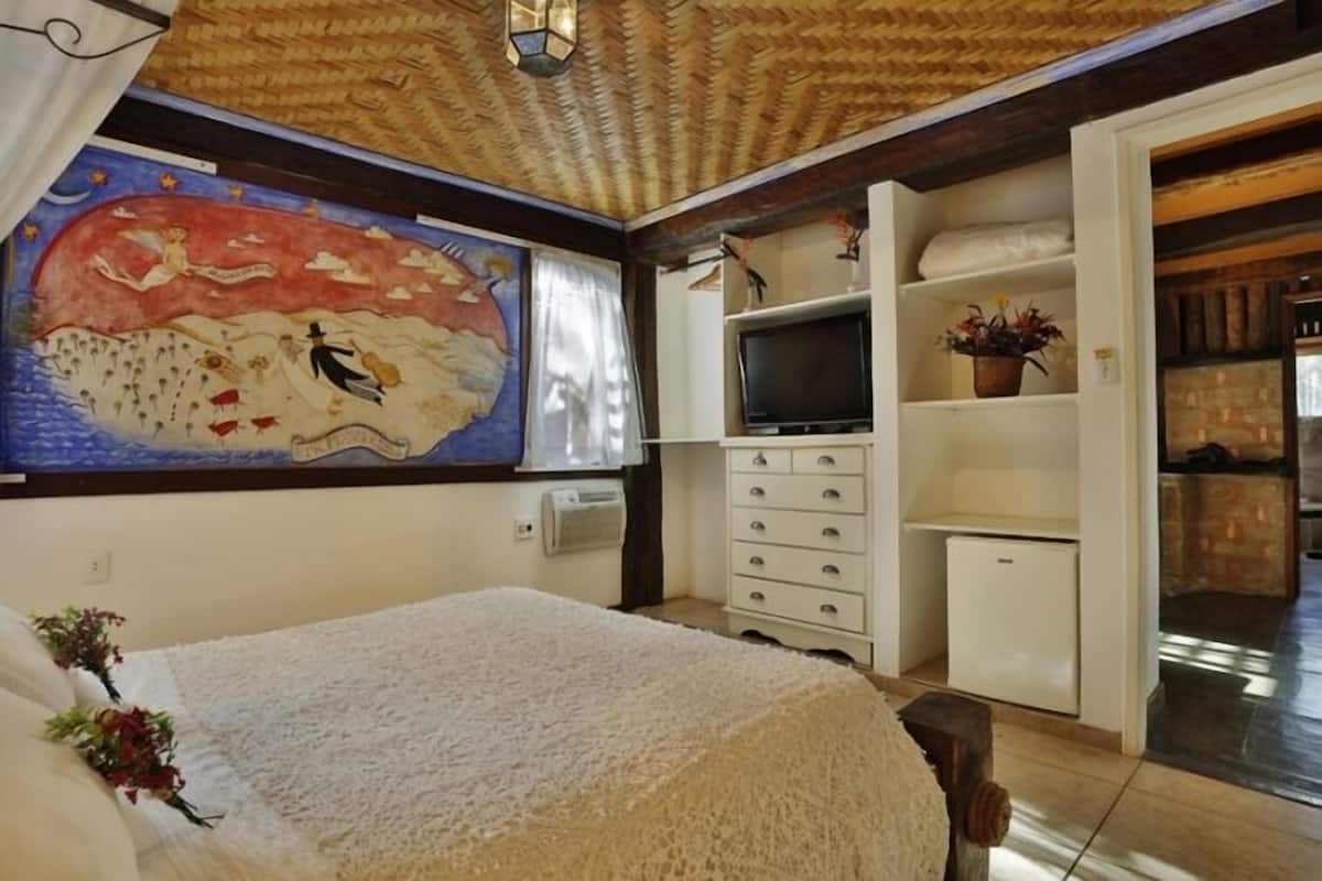 A bedroom with a bed, a television, a dresser, and a painting on the wall.