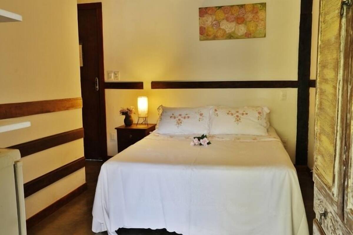 A neatly made bed with a floral pillow and a bedside lamp.