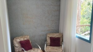 A room with two armchairs, a small table, and a window with curtains.