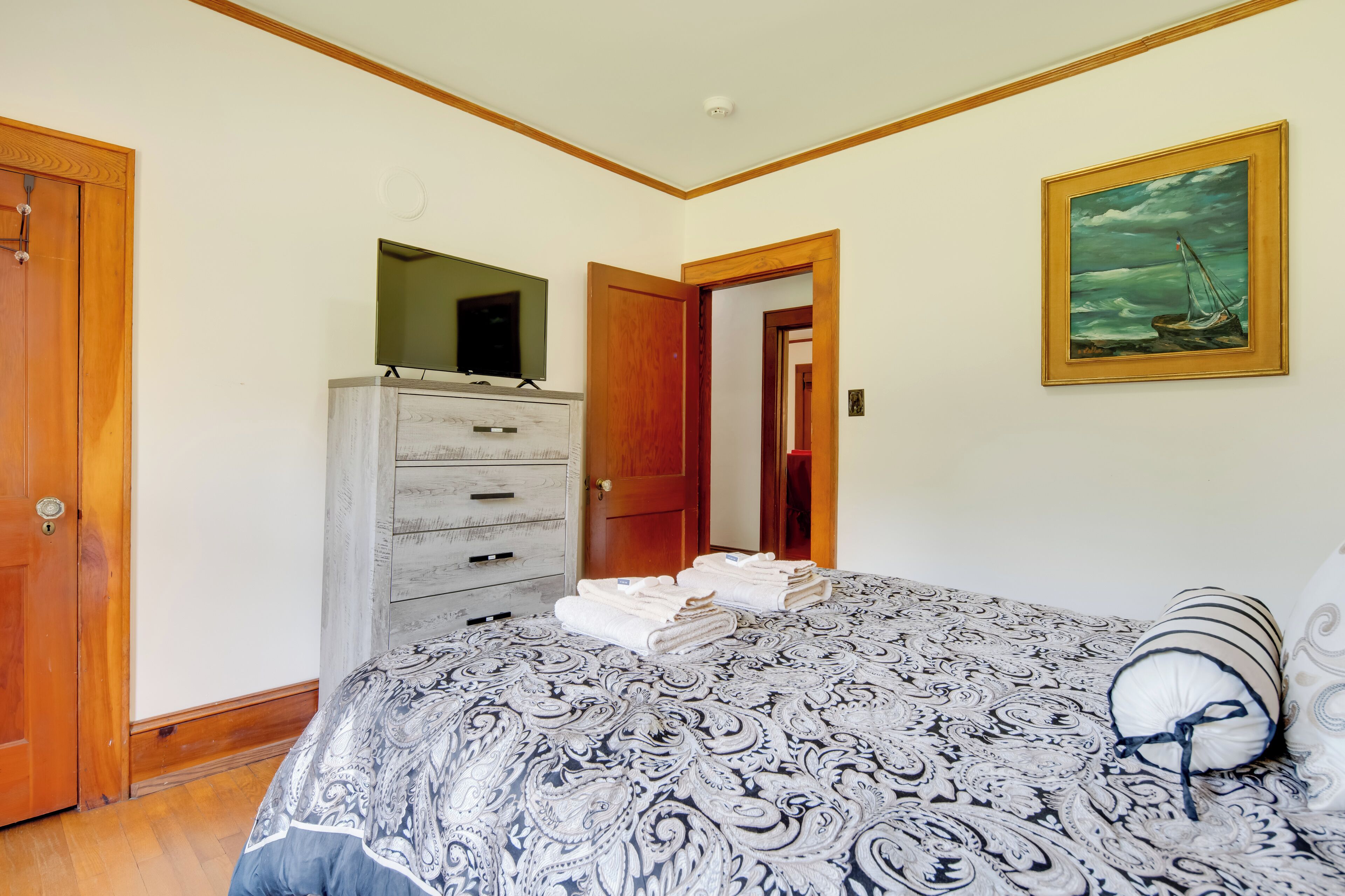 Ein Schlafzimmer mit Bett, Kommode, Spiegel und einem Gemälde an der Wand.