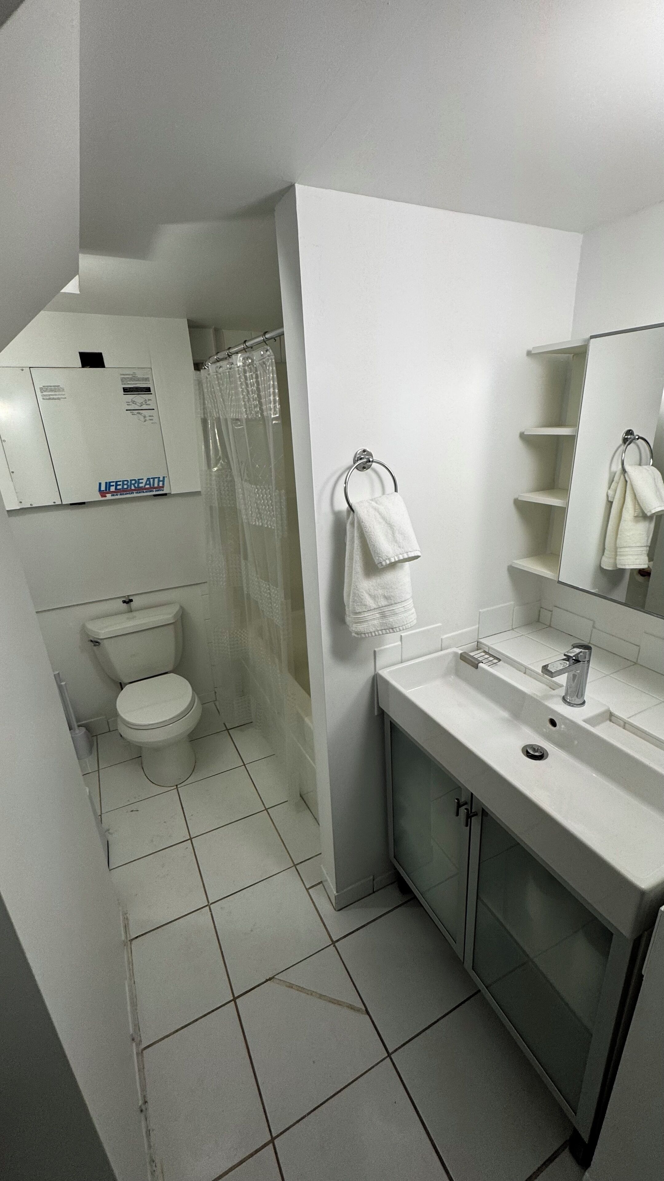 A modern bathroom with a toilet, shower, and sink.
