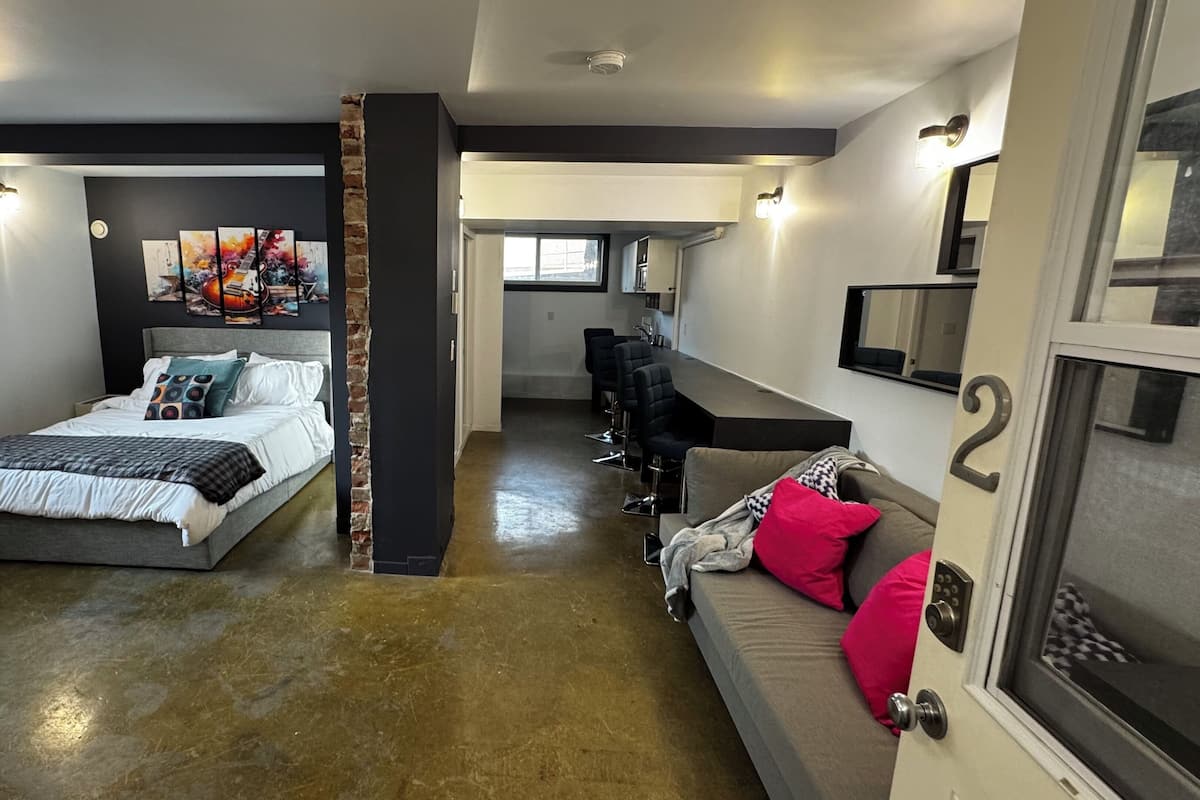 Un dormitorio moderno con cama, sofá y zona de comedor.
