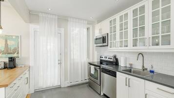 Una cocina moderna con armarios blancos, electrodomésticos de acero inoxidable y encimera negra.