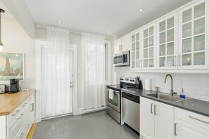 Een moderne keuken met witte kasten, roestvrijstalen apparatuur en een zwart aanrecht.
