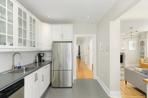 A modern kitchen with white cabinetry, a stainless steel refrigerator, and a dishwasher.