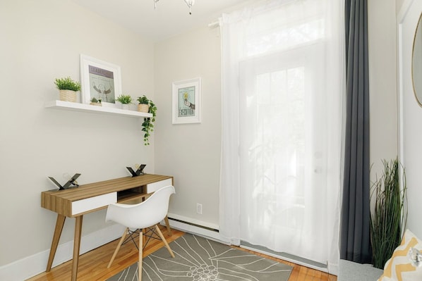 A room with a wooden desk, white chair, and two wall-mounted shelves with plants.