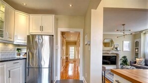 Una cocina moderna con electrodomésticos de acero inoxidable, piso de madera y vista al comedor.