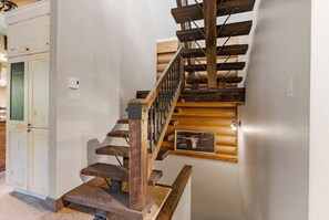 Una escalera de madera con barandilla de metal que lleva a una plataforma.