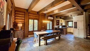 Un intérieur spacieux de chalet en bois, comprenant une grande table à manger, un coin cuisine et un espace salon confortable.