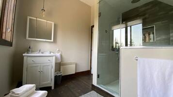 Ein modernes Badezimmer mit Duschkabine aus Glas, einem weißen Waschbecken und einem Spiegel über dem Waschtisch.