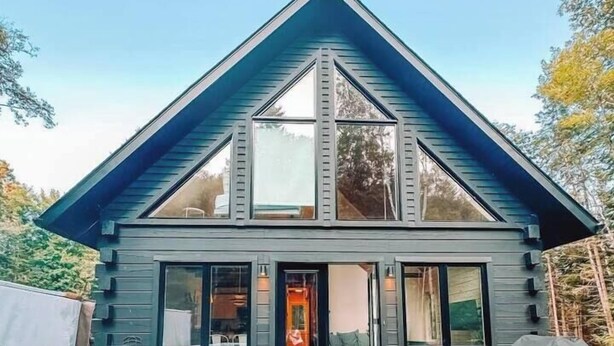 Une maison moderne à deux étages dotée d’une grande terrasse, d’un jacuzzi et d’une table de pique-nique.