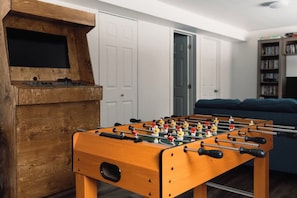 Una mesa de fútbolín en una habitación con una estantería y una puerta al fondo.