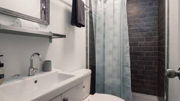 Ein Badezimmer mit weißem Waschbecken, Toilette und Dusche mit gemustertem Vorhang.