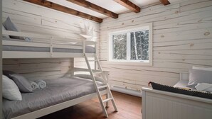Une chambre avec un lit superposé, une échelle, une fenêtre donnant sur des arbres et une commode blanche.