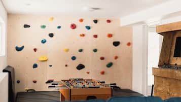 A room with a climbing wall, a foosball table, and a wooden cabinet.