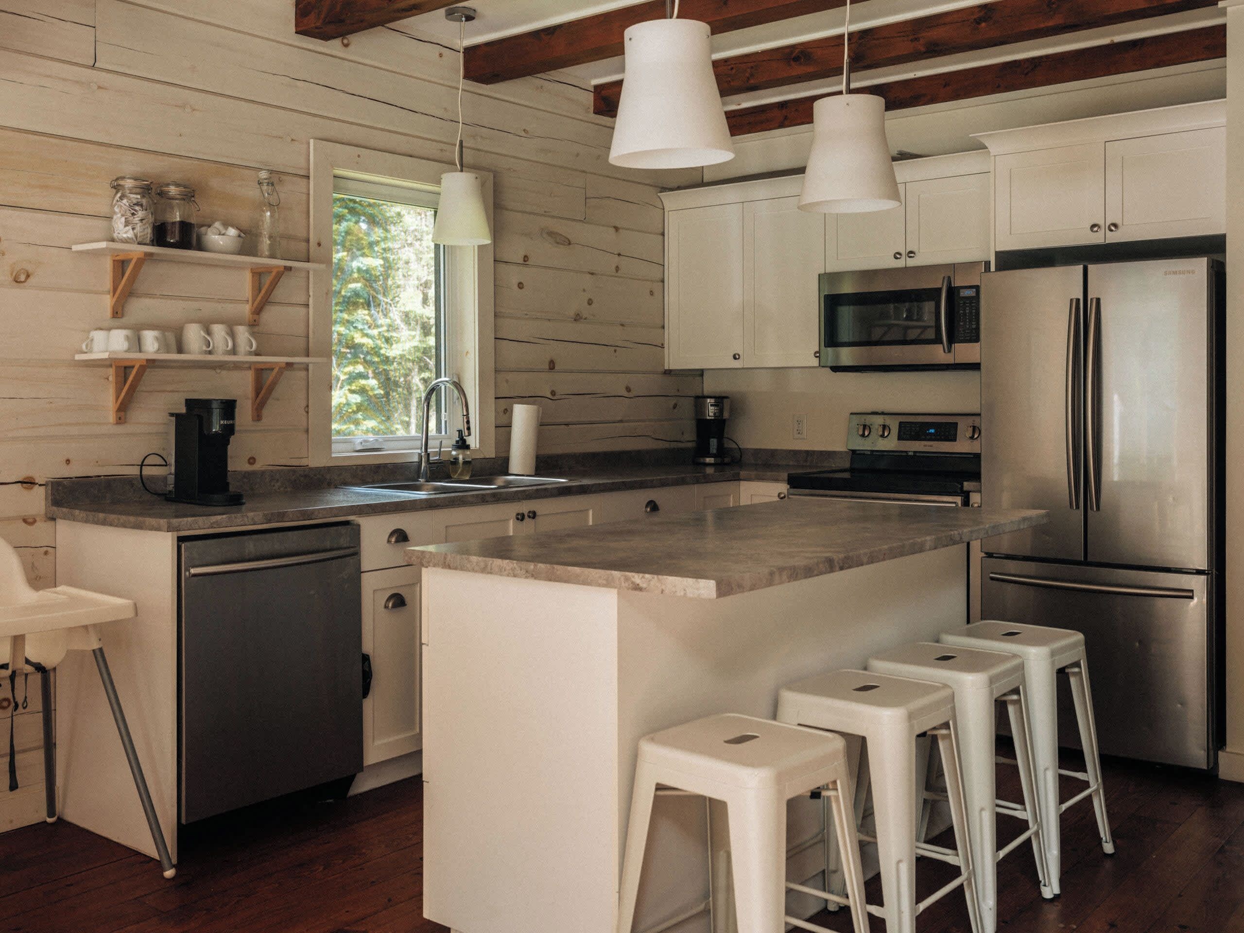 Una cocina moderna con gabinetes blancos, electrodomésticos de acero inoxidable y una isla central con taburetes de bar.