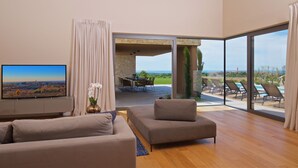 A modern living room with a flat-screen TV, a sofa, and a dining area with chairs and a table. - Luxury villa with pool and panoramic views - the perfect vacation in the heart of Istria (Brtonigla)