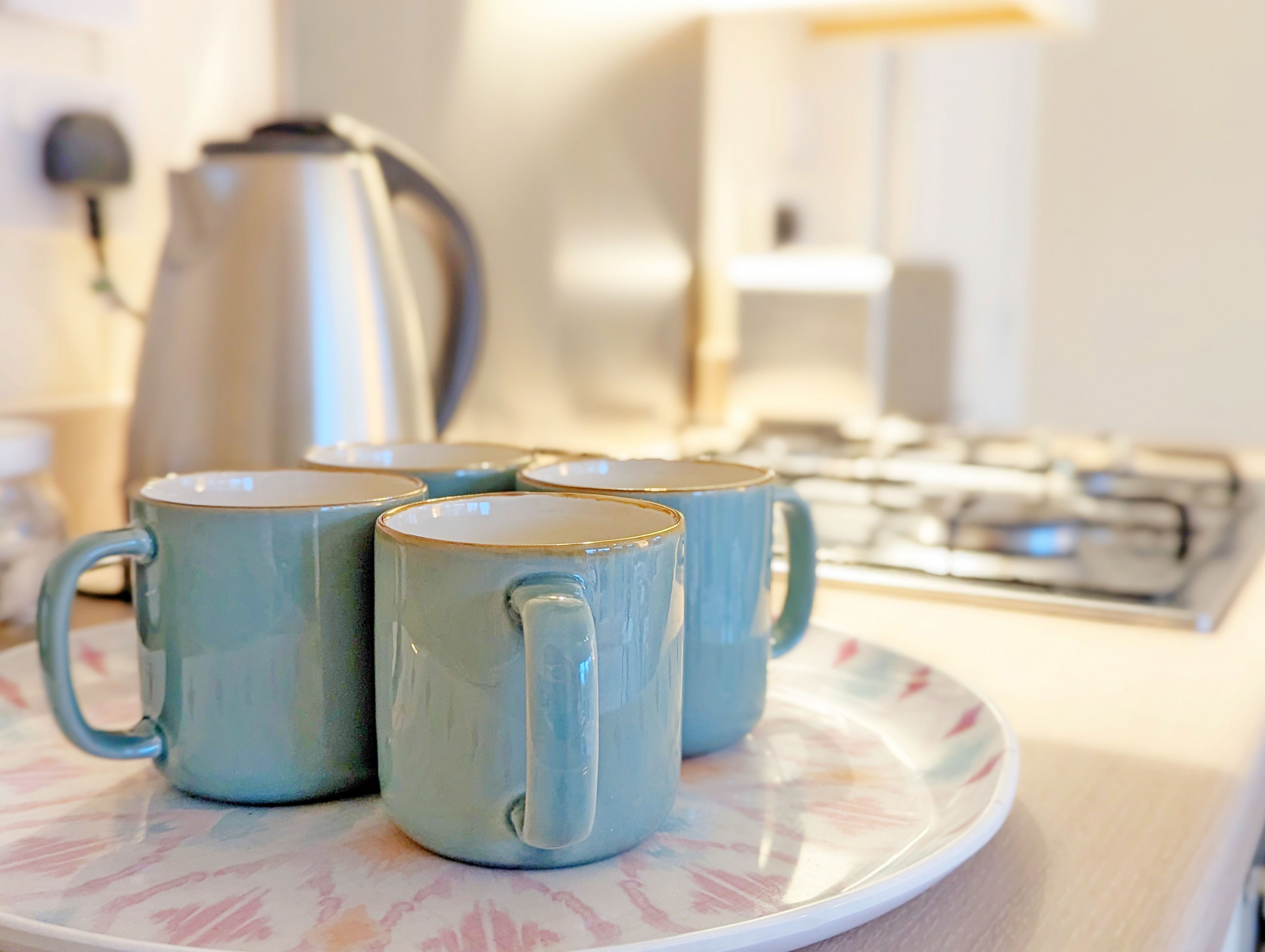 Un comptoir de cuisine avec une assiette contenant quatre tasses bleues et une machine à café en arrière-plan.