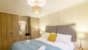 Een hotelkamer met een groot bed, een kledingkast, een nachtkastje met een lamp en een plafondlamp.