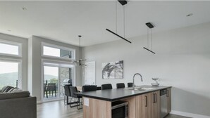Una cocina moderna con una isla central, un comedor con sillas y un amplio ventanal con vistas panorámicas.
