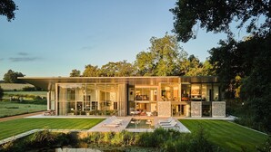 A modern house with a glass facade, a swimming pool, and a well-maintained lawn. - A country house that sleeps 14 guests  in 7 bedrooms (Avington)