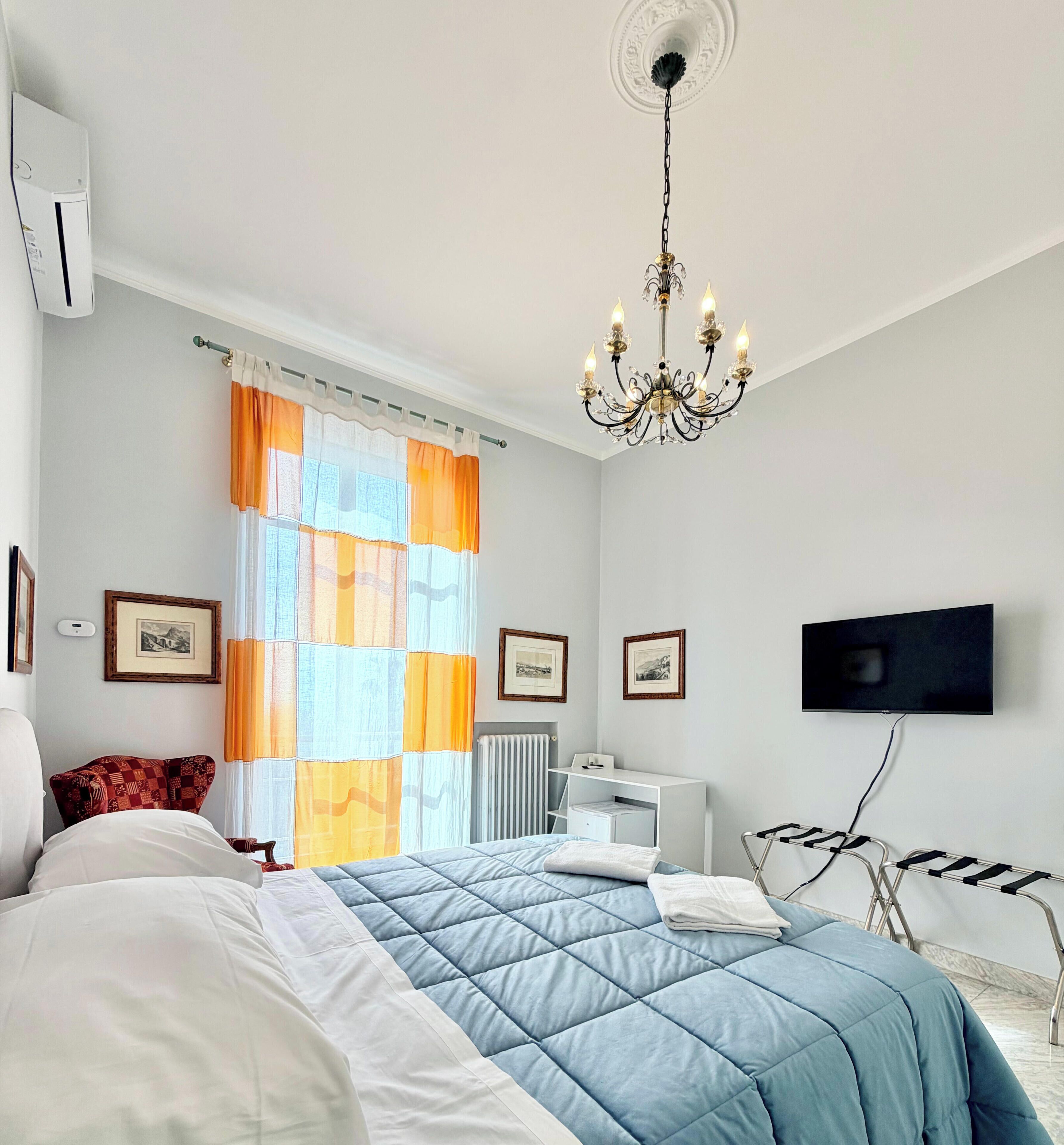 Une chambre à coucher avec un lit, un radiateur, une télévision et un lustre.