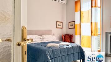 Un dormitorio con cama, una lámpara de araña, una silla y una ventana con cortinas.