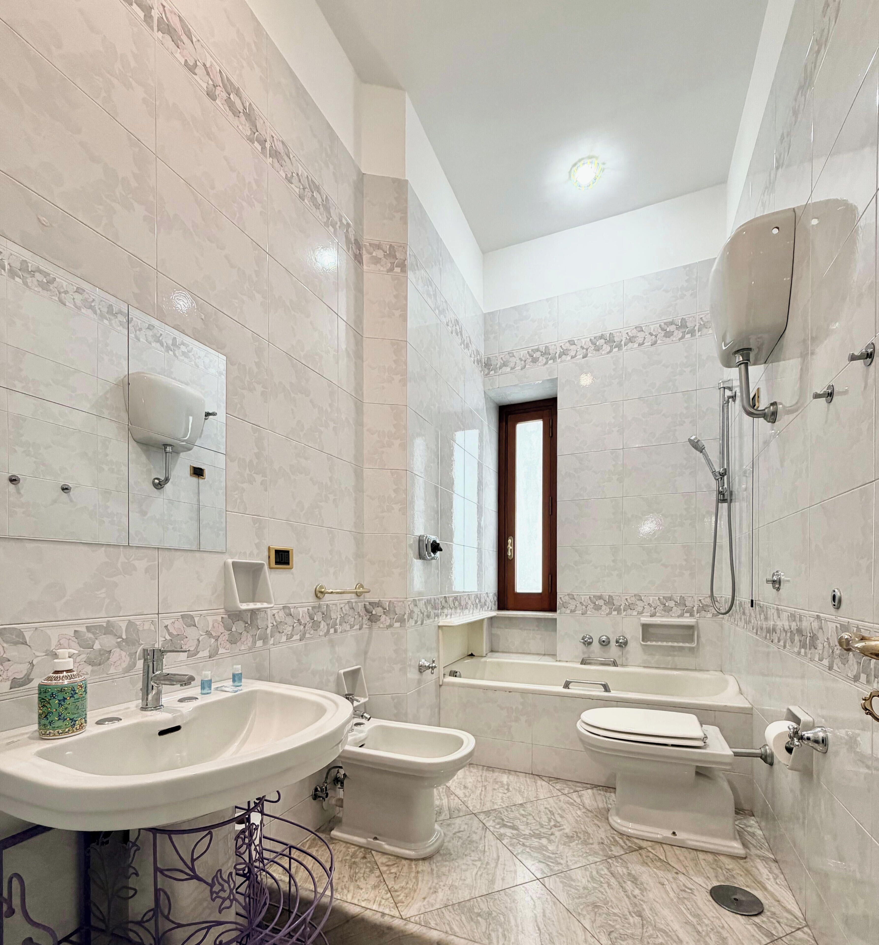 Een badkamer met een wastafel, bidet, toilet, bad en douche.
