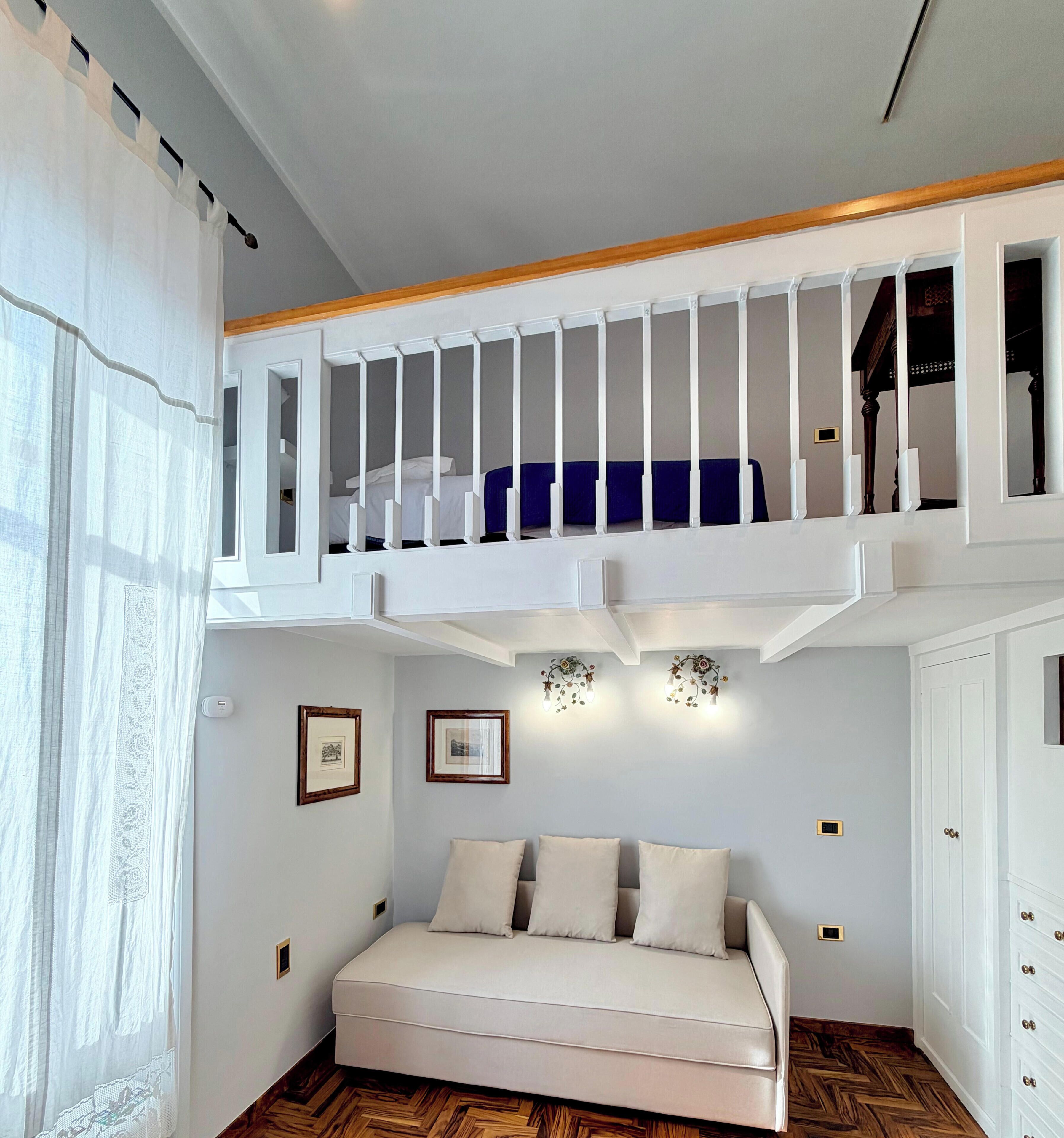 A room with a bunk bed, a sofa, and a small desk.