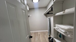 A walk-in closet with shelves for folded clothes, a hanging rack, and a storage bin.