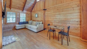 A log cabin interior with a wooden ceiling, a sofa, a dining table with chairs, and a clock on the wall. - < 1 Mi to Casinos: Countryside Louisiana Getaway! (Duson)