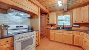 A kitchen with wooden cabinets, a white stove, and a brick wall. - < 1 Mi to Casinos: Countryside Louisiana Getaway! (Duson)