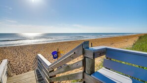 A wooden staircase leading to a beach with a bench and two buckets. - Walk to Shore + Pier: Family Home in Ormond Beach (Ormond Beach)