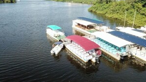 A riverfront with several boats docked, surrounded by greenery and buildings in the background. - Apart hotel Barra First  (Rio de Janeiro)