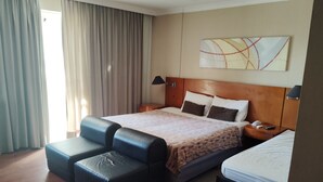 A hotel room with a large bed, a sofa, a desk, and a nightstand. - Apart hotel Barra First  (Rio de Janeiro)