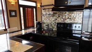 Una cocina con estufa negra, microondas y lavamanos con encimera de granito.