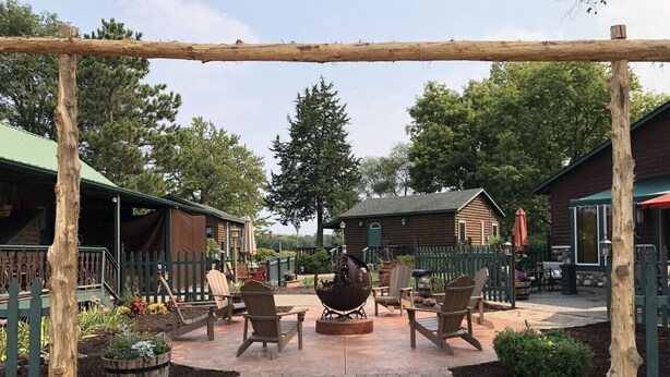 Un patio con mobiliario exterior, un brasero y una valla de madera.