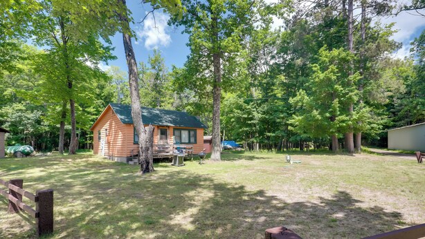 A cabin with a green roof, surrounded by trees and a grassy yard. - South Twin Lake Cabin w/ Dock, Steps to Water (Conover)
