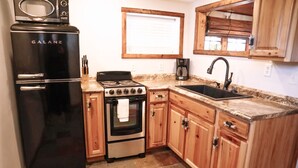 A compact kitchen with a black Galanz refrigerator, a stove, and a sink.