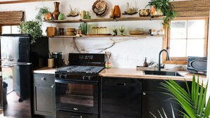 Eine moderne Küche mit schwarzen Geräten, Holz Arbeitsplatten und verschiedenen dekorativen Gegenständen auf Regalen.