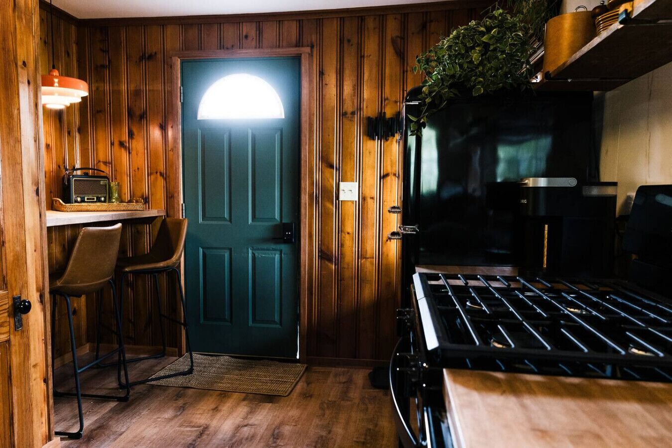 Une cuisine compacte avec une porte en bois, un petit coin bar équipé d’une radio et une cuisinière.