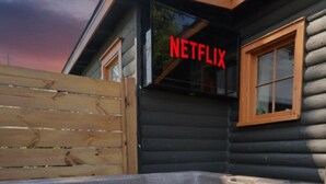 Eine Holzblockhütte mit Whirlpool und einem Schild mit der Aufschrift 'NETFLIX'.