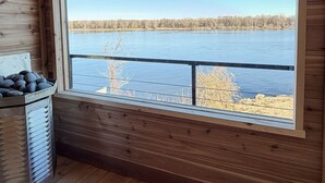 A cabin with a large window offering a view of a lake and forest.