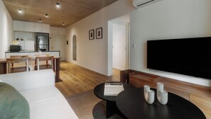 A modern living room with a flat-screen TV, a dining area with wooden furniture, and a kitchen in the background. - Hestia at Nuñez Vuelta de obligado 3000 (Buenos Aires)