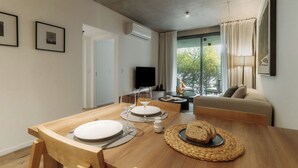 A dining area with a wooden table, chairs, and a TV in the background. - Hestia at Nuñez Vuelta de obligado 3000 (Buenos Aires)