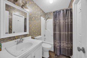 Un baño con lavamanos, inodoro y bañera blancos.
