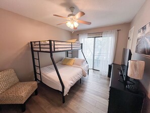 Habitación con literas, ventilador de techo, escritorio con computadora y una silla.